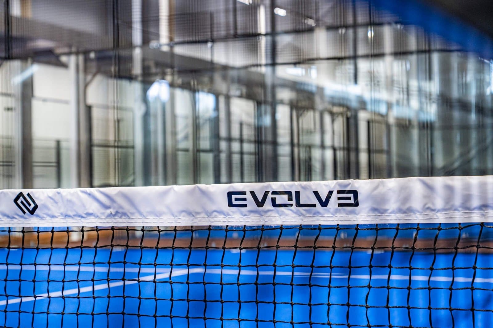 Evolve branded net across the blue surface of a padel court